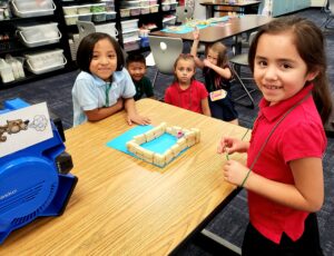 students constructing a model of a straw, stick, and brick homes from the Three Little Pigs