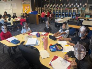 4th grade students sitting around a table dressed as serfs and knights of the Middle Ages