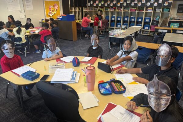 4th grade students sitting around a table dressed as serfs and knights of the Middle Ages