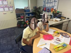4th grade students sitting around a table dressed as serfs and knights of the Middle Ages