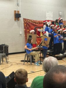 Student playing the guitar while the choir sings