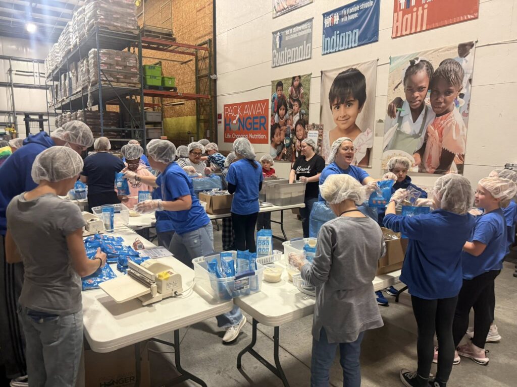 GV student council, staff, and families scooping, weighing, sealing, and packing nutritious meals for those in need