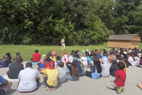5th grade students sitting outside and listening to a presentation from Mr. Caddell about the Civil War.