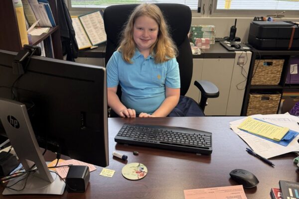 Delilah sitting at the principal's desk