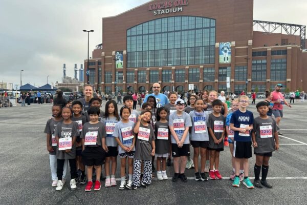 a rendering of the Glenns Valley running club standing in front of Lucas Oil Stadium with their coaches Mrs. Beard and Mr. wood