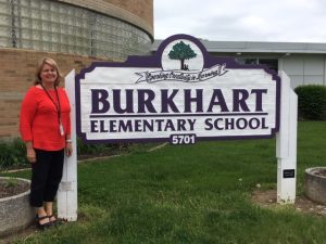 Joann Ahman in front of burkhart elementary sign