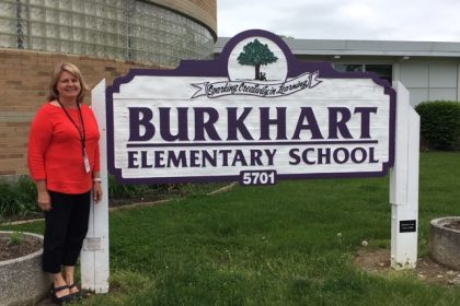 Joann Ahman in front of burkhart elementary sign