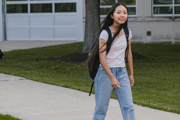 A Perry Township Schools student wearing a backpack walks along a sidewalk on the University of Indianapolis campus during filming for the Innovation & Entrepreneurship Program. Alternative: