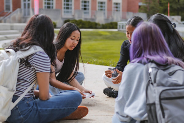 Perry Township Schools students sit together on the University of Indianapolis campus playing cards between filming sessions for the Innovation & Entrepreneurship Program.