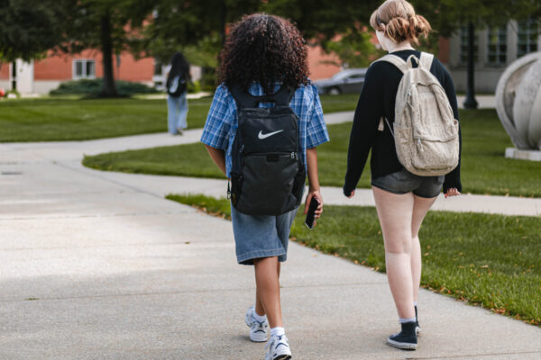 Two Perry Township Schools students wearing backpacks walk together on the University of Indianapolis campus during filming for the Innovation & Entrepreneurship Program. Alternative: