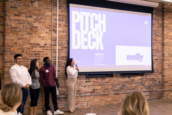 Students presenting their pitch to Mally Coffee Roasters, stakeholders, leadership, and judges.